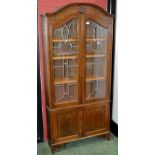 A 1930/40's oak bookcase cabinet, dome top, arched lead glazed doors enclosing shelving,