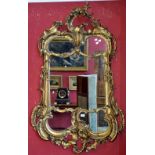 A gilt Rococo shaped mirror, foliate pediment, swags and foliage to frame.