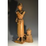 A 19th century Folk Art figure, carved as a bee keeper, she stands beside the skep,