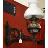 A pair of cast iron wall oil lamp brackets, complete with reservoirs and shades,