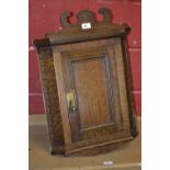 A small oak wall mounted corner cupboard, shaped pediment, canted angles, dentil border, panel door,