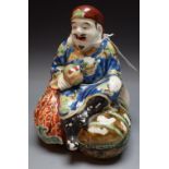 A Japanese porcelain figure, of an artisan seated on a bundle of sacks, 14cm high,