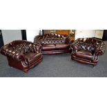 A Thomas Lloyd ox blood leather Chesterfield style three piece suite comprising two seat button