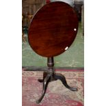 A George III mahogany tilt-top table, circular top, canon barrel column, tripod base.