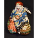 A Japanese porcelain figure, of an artisan seated on a bundle of sacks, 14cm high,