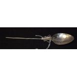 An 18th century silver coloured metal spoon, the bowl chased with a stylised flower,