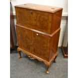 A contemporary burr walnut and mahogany cocktail cabinet, fall front enclosing mirrored interior,