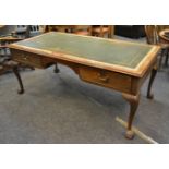 A George III-style mahogany library table, tooled leather writing surface, arched frieze,