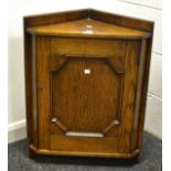 An early 20th Century oak corner cupboard cross banded panelled door,