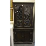 A Jacobean Revival oak corner cabinet, two astral glazed doors enclosing two shelves,