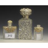 An Edwardian silver mounted smelling salts bottle, the domed cover embossed with foliate scrolls,