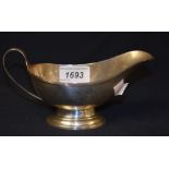 A George V silver sauce boat, reeded decoration, scroll handle, pedestal foot, London 1936,