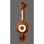 A Victorian oak barometer, 19cm white dial, the case heavily carved with bold pea pods,