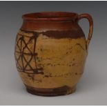 An 18th century slipware jug, with geometric motif in brown on an ochre ground, strap handle,