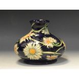 A contemporary Moorcroft compressed ovoid vase, tube lined with scrolling daisies, on a blue ground,