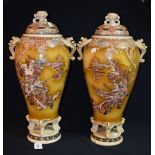 A pair of large lidded Satsuma vases standing on circular bases, raised on four feet,