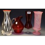 A pink glass footed cylindrical vase, enamelled white decoration; a ruby glass jug,