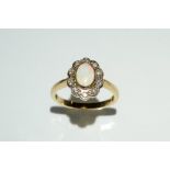 An opal and diamond cluster ring, central oval opal surrounded by a band of ten diamond accents,