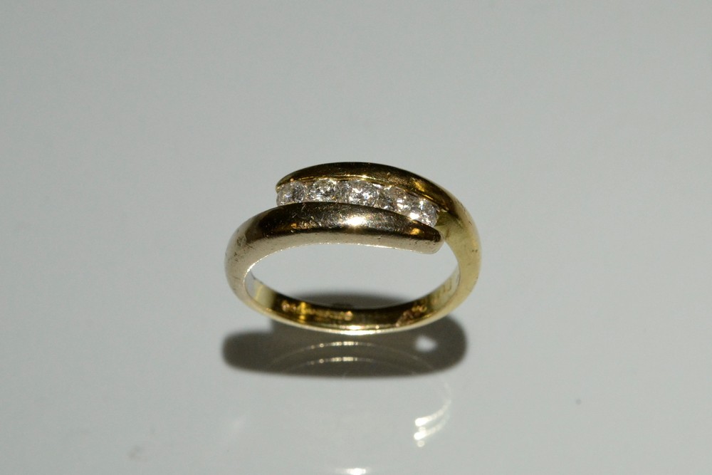 A diamond five stone ring, open ended channel inset with five round cut diamonds,