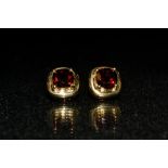 A pair of red garnet stud earrings, each with a single square cushion cut garnet,