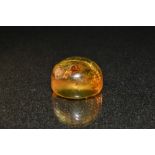 A free form amber cabochon, integral arachnid fossil, 24mm diameter, 5.