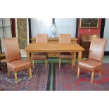 A modern light oak dining table and four leather upholstered dining chairs.