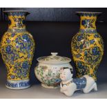 A pair of Chinese vases, decorated with dragons in blue on a mustard ground,