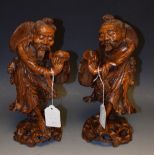 A pair of Chinese hardwood figures, of emaciated elders, each carrying a storage vessel,