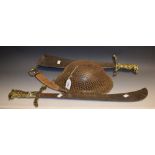 A WWII Brodie helmet with scrim netting; wall hanging sword with ornate brass hilt and crossguard;