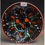 A Poole Pottery Adephis bowl, decorated with a black, burnt orange and green seven petal flower,