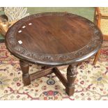 An oak occasional table, circular top, lunette carved border, turned and blocked supports.