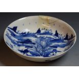 An 18th century circular dish, decorated in underglaze blue with bull, keeper, huts, mountains,