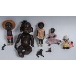 An early 20th century composition doll, as a black girl, her head with tufts of woolen hair,