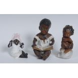 An early 20th century Continental bisque porcelain figure, of a black infant, at a spelling book,