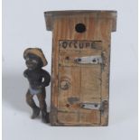An early 20th century cold painted novelty, as a young black boy beside an outhouse,
