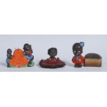 A Japanese novelty pin cushion, moulded with orange spade, flanked by two comical black children,