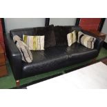 A modern designer two seater black leather sofa of large proportions.