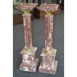 A pair of variegated rouge marble torcheres, moulded square tops, Corinthian cast brass capitals,