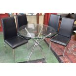 A modern designer circular glass and chrome dining table and four chairs