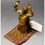 A reproduction Bergman type cold painted metal, figure at prayer on prayer mat,