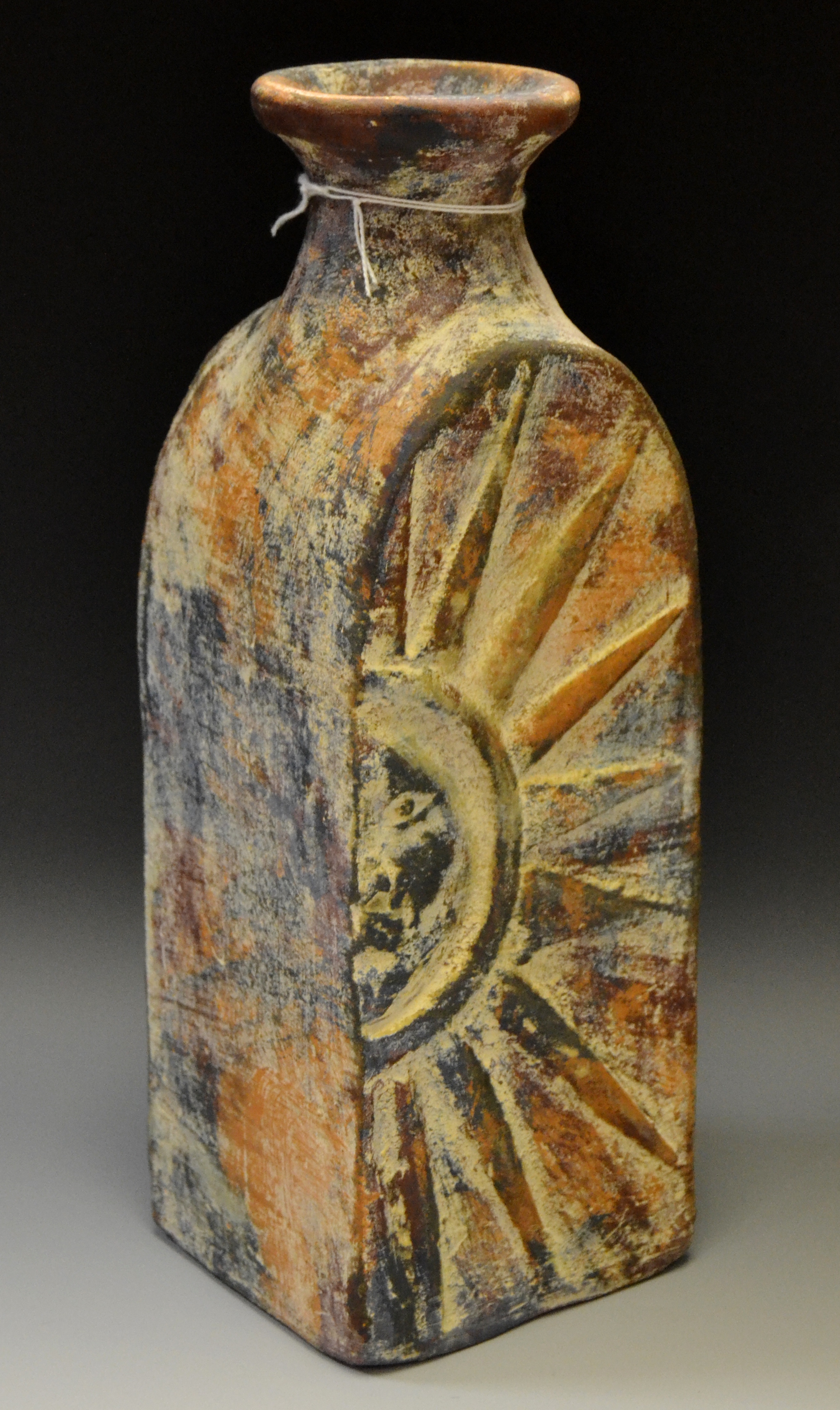 An Art pottery red clay vase, in relief with sun, mottled in orange, blue and red, 28.