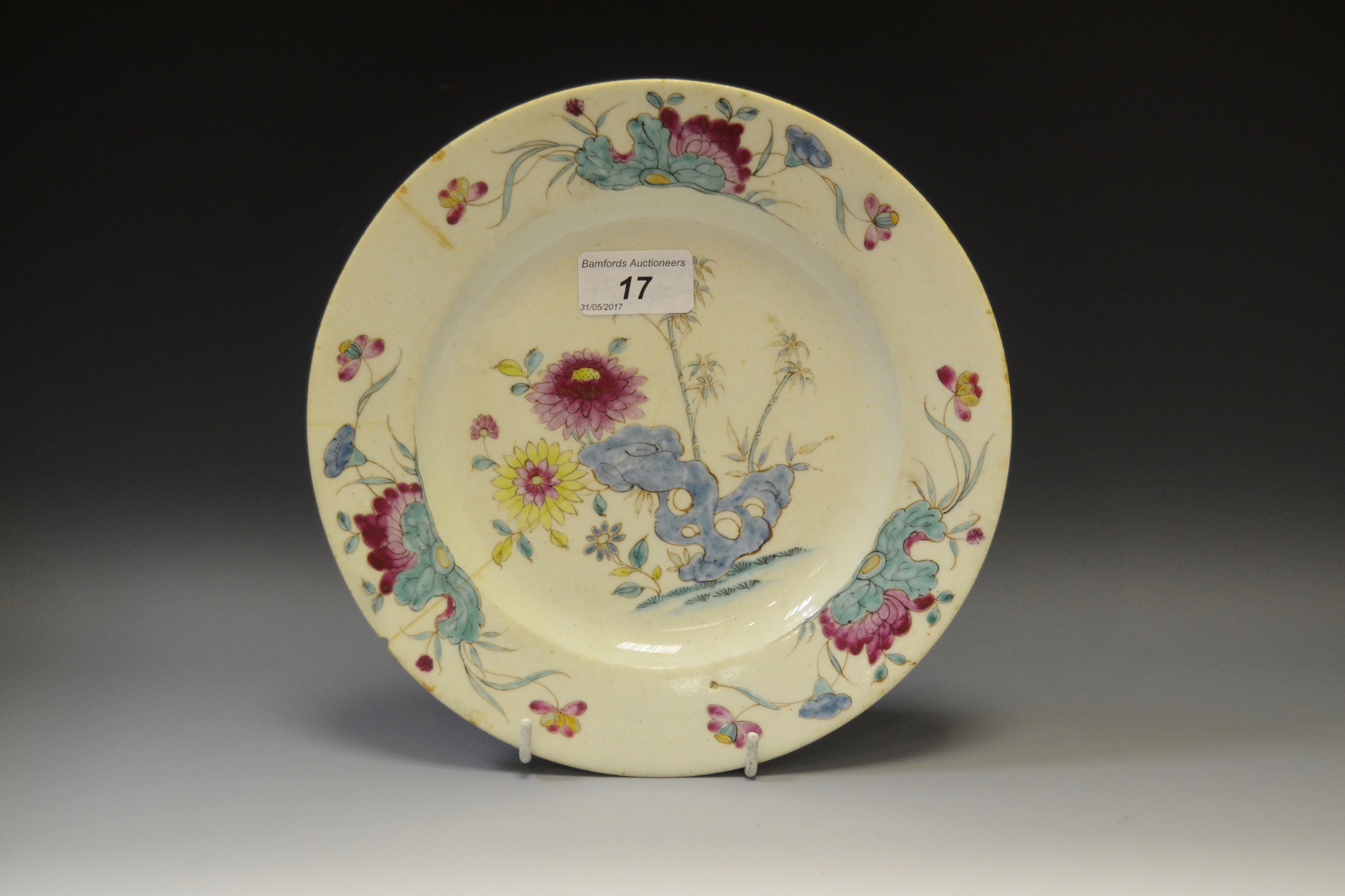 An 18th century Bow circular plate, painted in Famille Rose manner with holed rock,