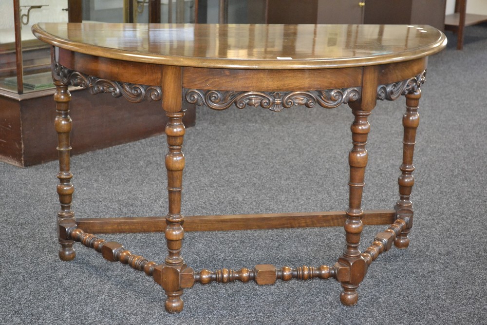 A mahogany demi-lune table, deep frieze, pierced and carved S - scroll skirt, turned legs,