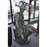 A green patinated cast metal figure of a seated soldier. 127cm high.