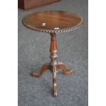 A reproduction mahogany tilt top tripod table, circular top, gadrooned border, turned column,
