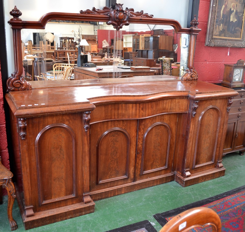 A large Victorian mahogany break front mirror back sideboard, the arched mirror with carved crest,