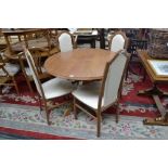 A modern circular extending dining table and four high back dining chairs.