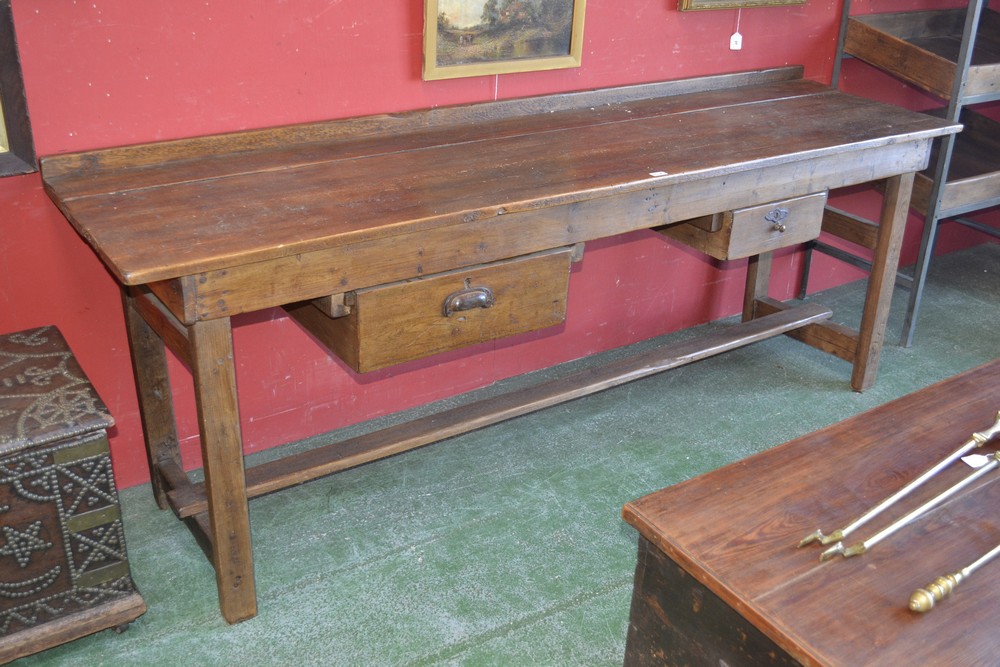 A rustic stained pine and oak country kitchen table, galleried back, plank top, two deep drawers,