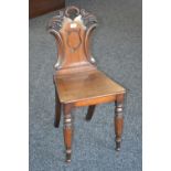 A William IV mahogany hall chair, carved waisted back, shield cartouche, wooden seat,