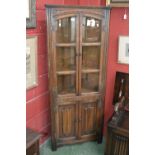 An Old Charm oak corner cabinet, glazed doors to top, linenfold panel doors to base.
